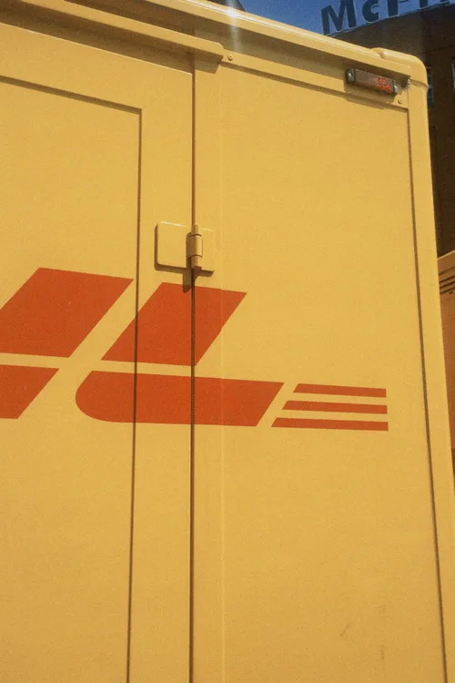 The back of a yellow delivery truck with a red logo.