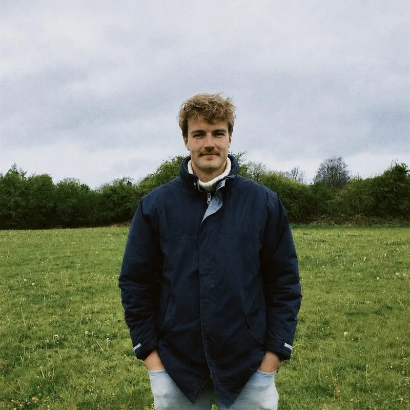 Tom Simms in a green field, wearing a navy jacket.