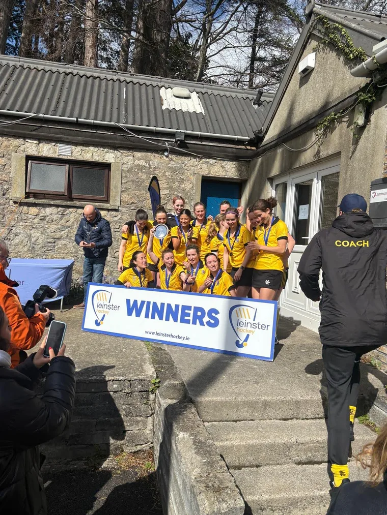 The Pembroke Women's 3s team gathered behind a 'Winners' banner after a final.