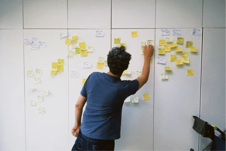 Clustering interview findings into themes with sticky notes on a wall.